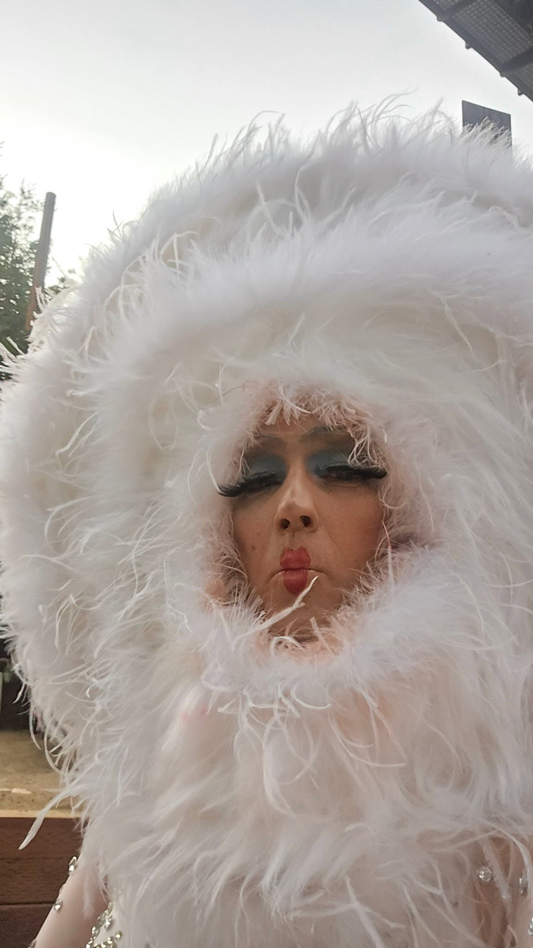 Maggie in a white feathered headdress and boa